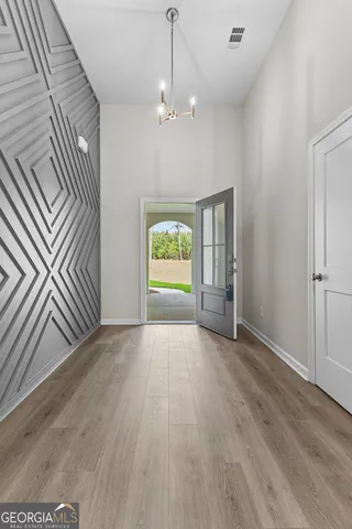 an empty room with wooden floor chandelier and windows