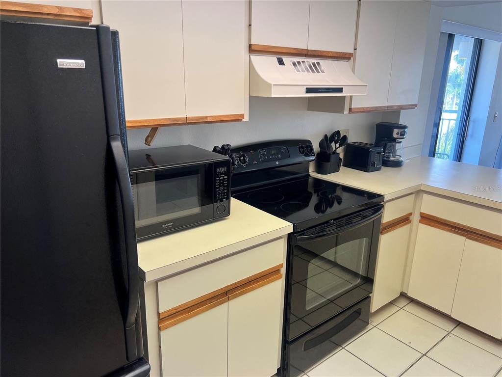 1001 Point Of Rocks Road, Unit 408 Sarasota, FL 34242 - Photo 6 of 34 a kitchen with a stove and white cabinets