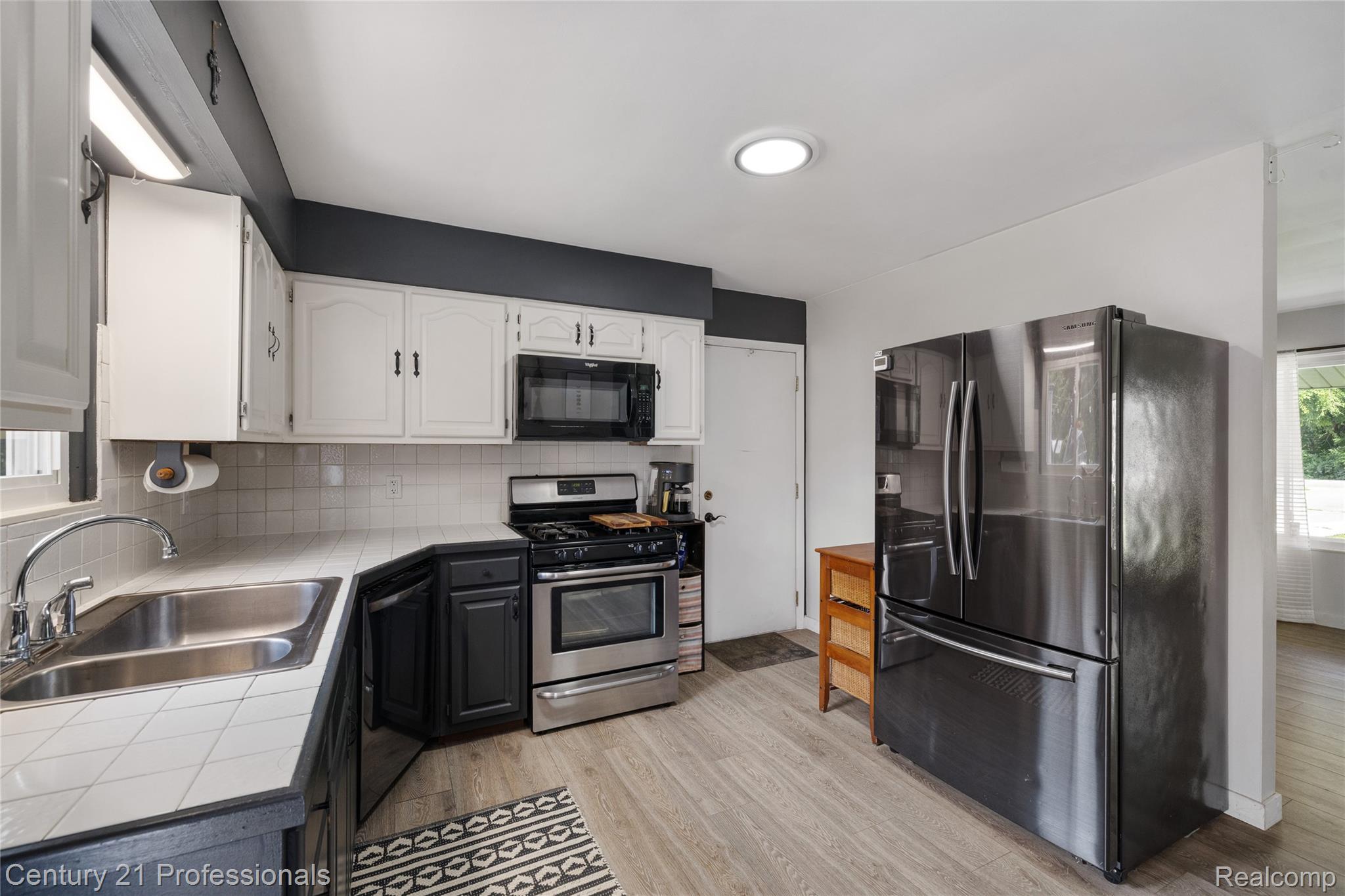15037 Hogan Road Linden, MI 48451 - Photo 11 of 38 Kitchen featuring white upper cabinetry, dark lower cabinetry, and stainless steel appliances
