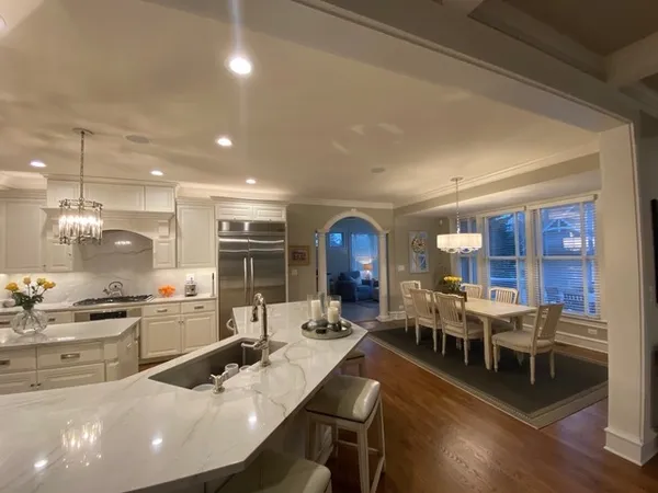 a kitchen with stainless steel appliances a dining table chairs and stove