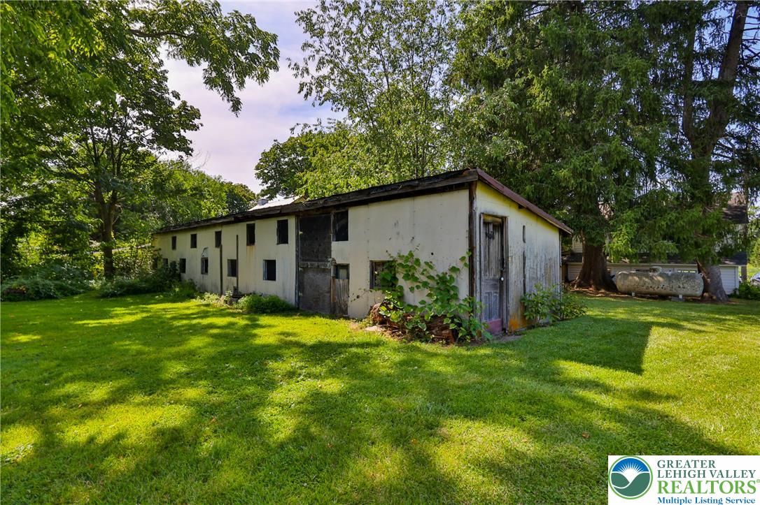 666 Point Phillips Road Bath, PA 18014 - Photo 60 of 68 Mature trees surround this rustic outbuilding, set amidst a vibrant green lawn.