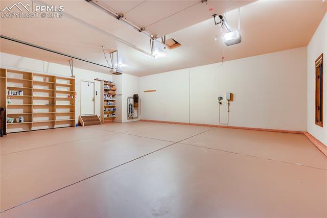 6155 Wilson Road Colorado Springs, CO 80919 - Photo 29 of 35 Fully finished 3-car garage is extra deep and has an included detailing vacuum attached to the far corner. Includes built-in shelves. Newly painted floor. Immaculate!