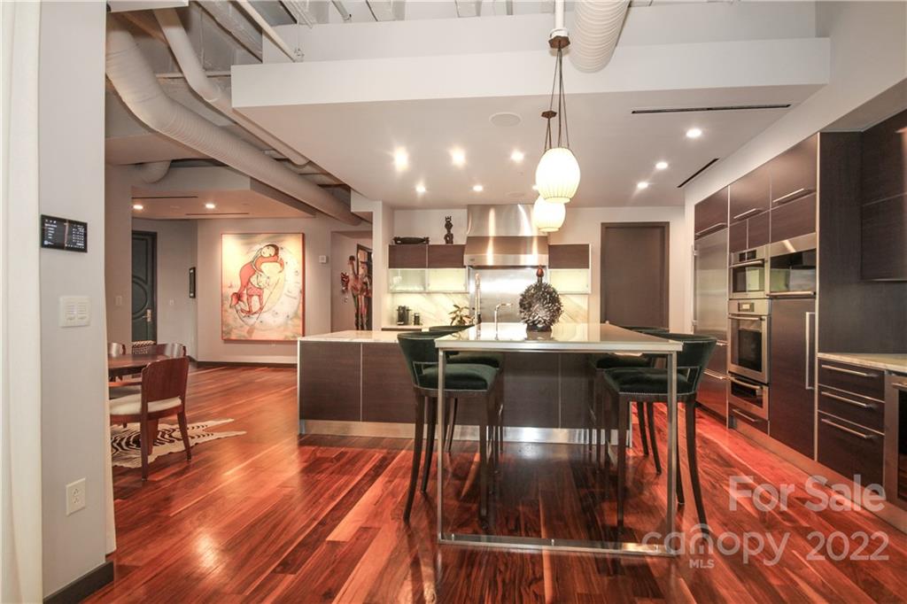 139 South Tryon Street Charlotte, NC 28202 - Photo 19 of 48 a kitchen with stainless steel appliances granite countertop a refrigerator a stove top oven a dining table and chairs with wooden floor