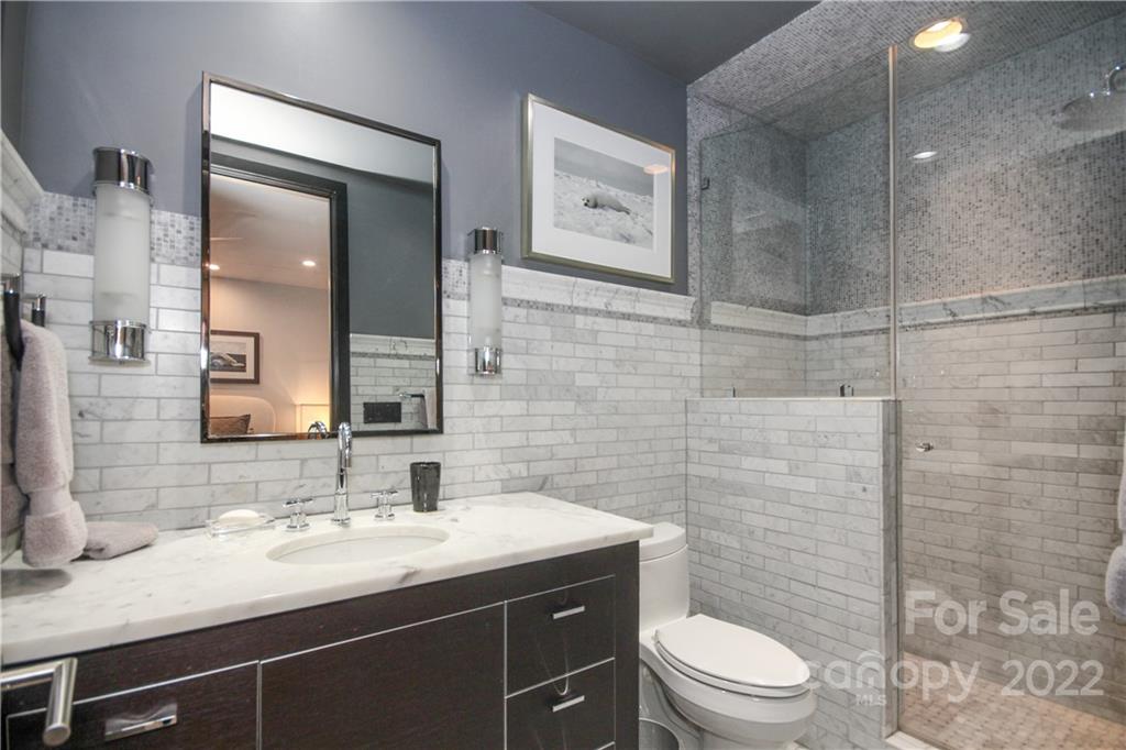 139 South Tryon Street Charlotte, NC 28202 - Photo 42 of 48 a bathroom with a granite countertop sink toilet a mirror and shower