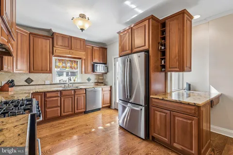 a kitchen with stainless steel appliances granite countertop a refrigerator a sink dishwasher a stove with wooden cabinets and floor