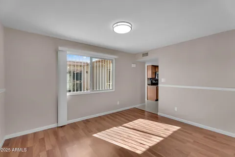 a view of an empty room with wooden floor and a window