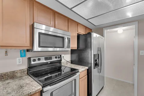 a kitchen with granite countertop a refrigerator and a stove top oven