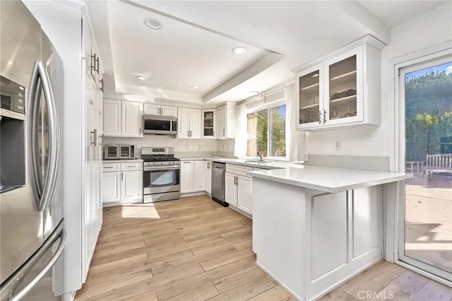 a kitchen with stainless steel appliances granite countertop a refrigerator a sink a stove top oven and a refrigerator