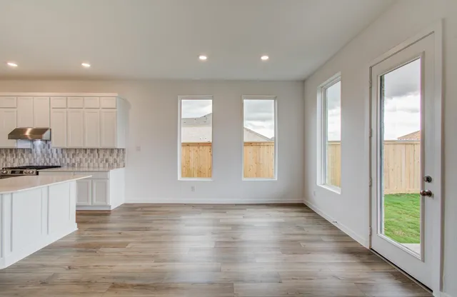a open kitchen with white cabinets and wooden floor