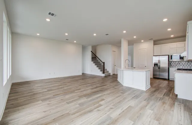 a view of kitchen with stainless steel appliances wooden floor dining table and chairs