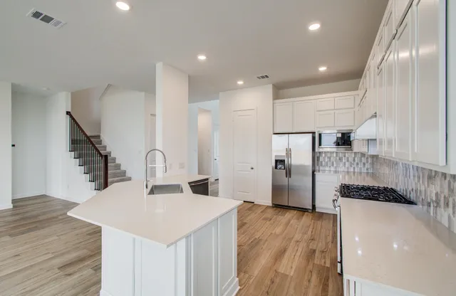 a kitchen with stainless steel appliances kitchen island granite countertop a refrigerator and a stove top oven