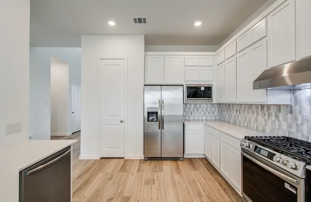 a kitchen with stainless steel appliances granite countertop a stove a refrigerator and a sink