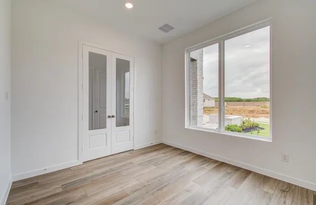 an empty room with wooden floor and windows