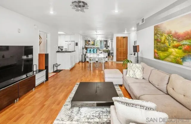 a living room with stainless steel appliances furniture and a flat screen tv