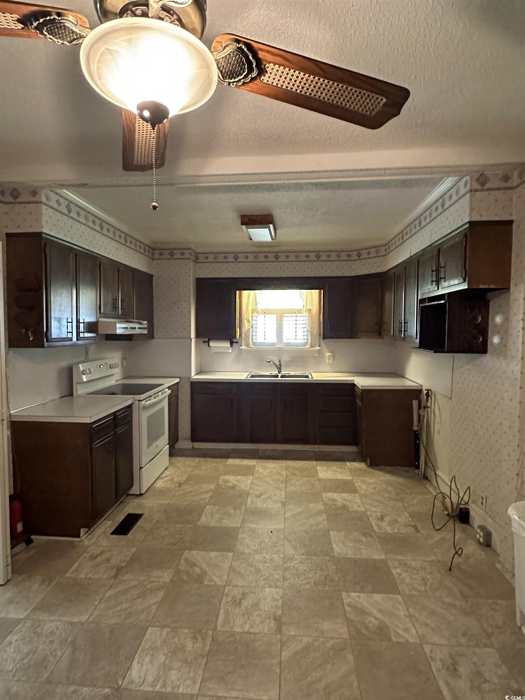 1357 Moss Street Georgetown, SC 29440 - Photo 5 of 13 Kitchen featuring wallpapered walls, dark brown cabinetry, light countertops, white electric range, and a textured ceiling