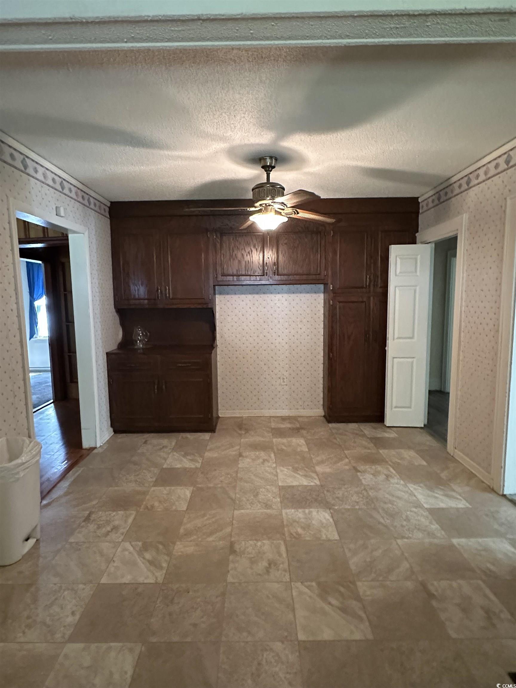 1357 Moss Street Georgetown, SC 29440 - Photo 6 of 13 Kitchen featuring wallpapered walls, dark brown cabinetry, a textured ceiling, ceiling fan, and stone finish floors