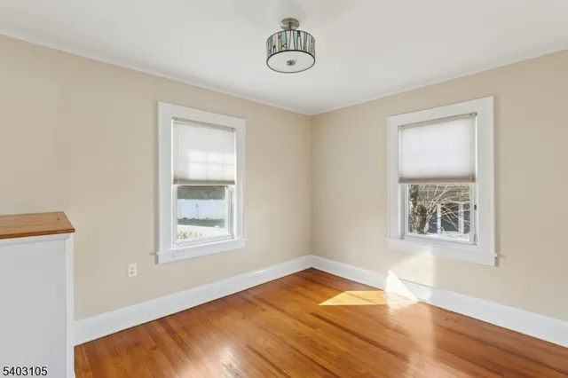 an empty room with wooden floor cabinet and windows