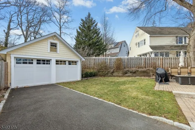 a view of backyard of house with wooden fence and a large tree