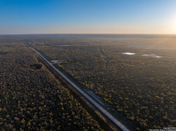 an aerial view of residential houses with outdoor space and trees