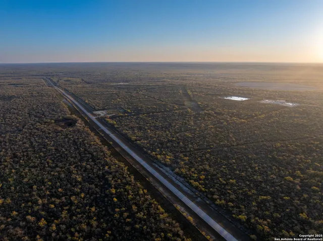 an aerial view of residential houses with outdoor space and trees
