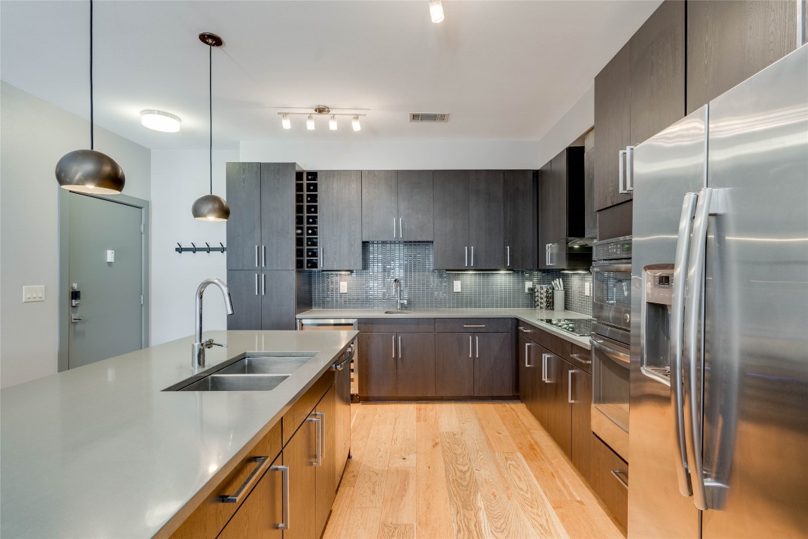 a large kitchen with granite countertop a sink a counter top space stainless steel appliances and cabinets