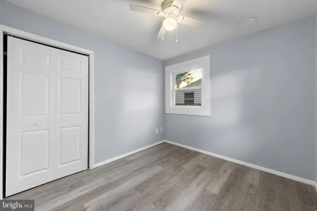 an empty room with wooden floor closet and windows