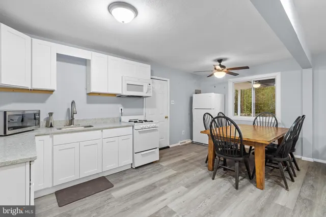 a kitchen with stainless steel appliances granite countertop a white table and chairs