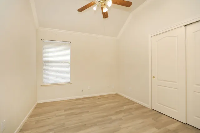 an empty room with a window and a ceiling fan