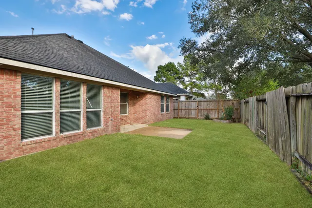 a view of a backyard with large trees and wooden fence