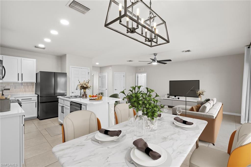 8149 Gopher Tortoise Trail Lehigh Acres, FL 33972 - Photo 15 of 50 a living room with stainless steel appliances furniture a chandelier and a view of kitchen