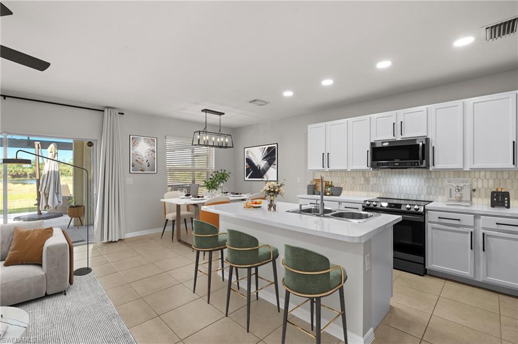 8149 Gopher Tortoise Trail Lehigh Acres, FL 33972 - Photo 19 of 50 a kitchen with stainless steel appliances granite countertop a stove top oven a sink dishwasher a dining table and chairs with wooden floor