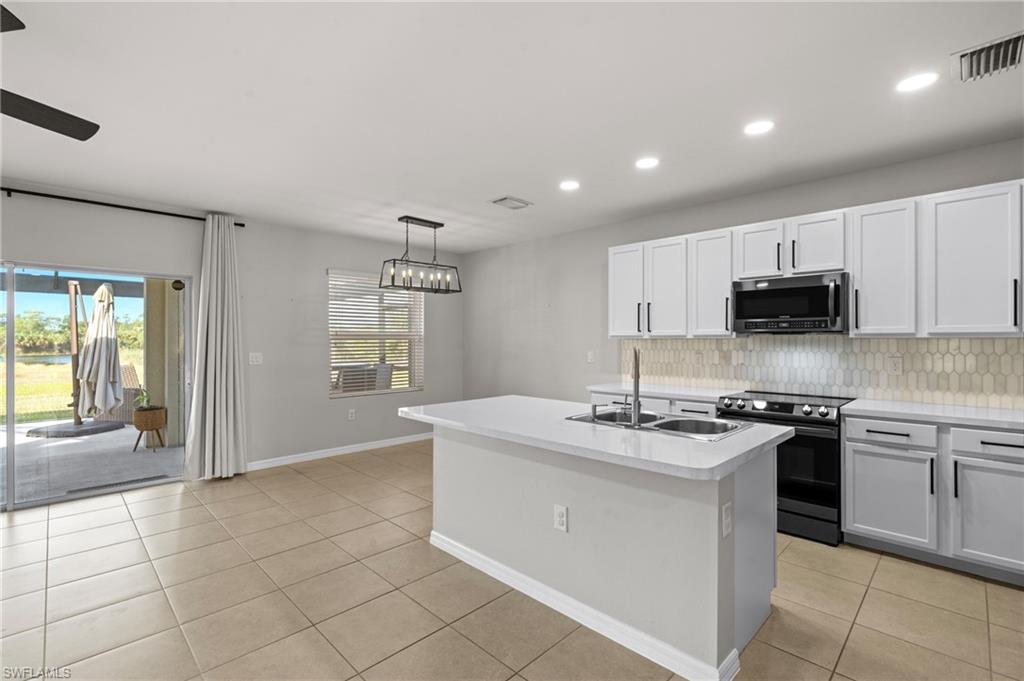 8149 Gopher Tortoise Trail Lehigh Acres, FL 33972 - Photo 20 of 50 a kitchen with stainless steel appliances granite countertop a sink and a stove