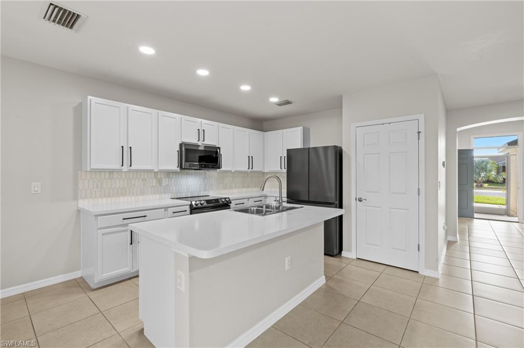 8149 Gopher Tortoise Trail Lehigh Acres, FL 33972 - Photo 21 of 50 a kitchen with stainless steel appliances a refrigerator stove microwave and sink