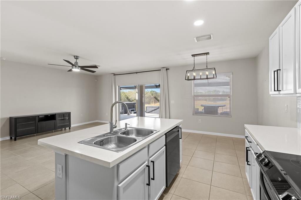8149 Gopher Tortoise Trail Lehigh Acres, FL 33972 - Photo 23 of 50 a kitchen that has a sink a stove and a table with wooden floor