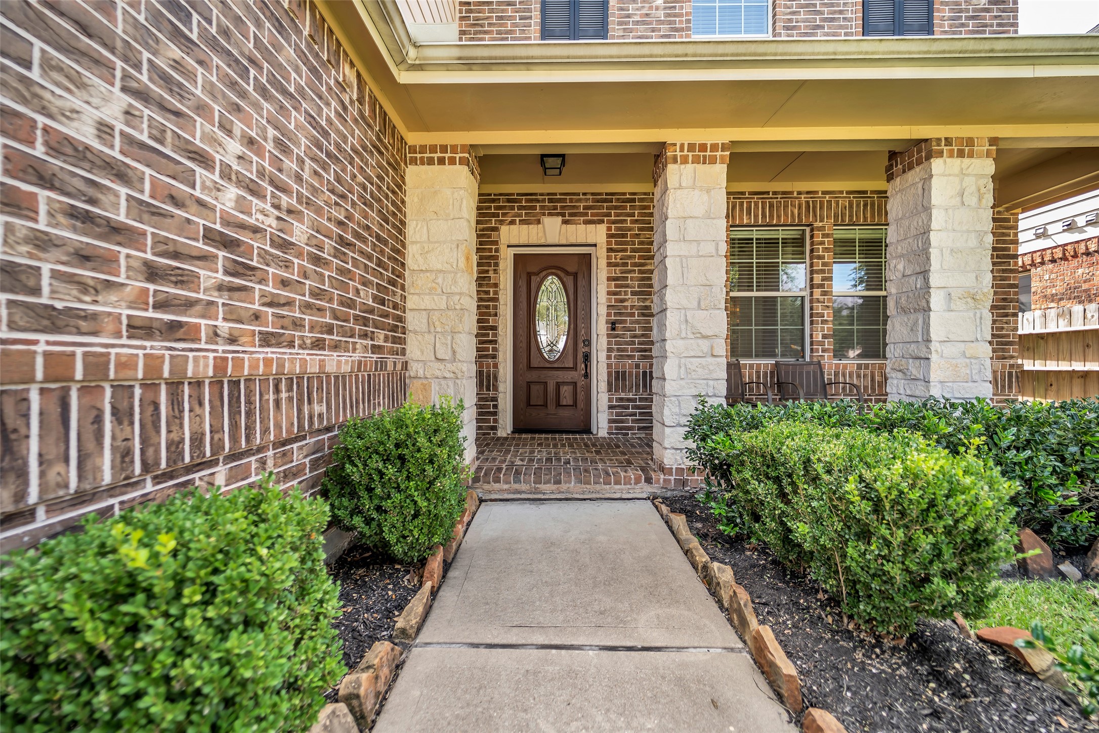 5406 Quarry Ridge Road Richmond, TX 77407 - Photo 3 of 36 Inviting covered front porch with stone columns, lush landscaping, and a beautiful entry door that creates a warm welcome home.