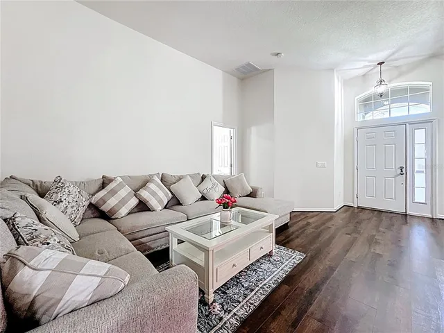a view of a dining room and livingroom with furniture wooden floor a chandelier