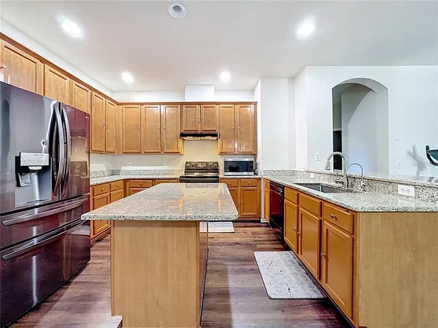 a kitchen with stainless steel appliances granite countertop a sink a stove and a microwave oven with wooden floor