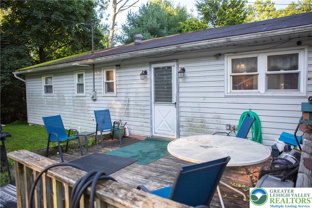 8657 South Loop Road Slatington, PA 18080 - Photo 21 of 32 Mature trees frame the wooden deck and rear entrance of this single-level home.