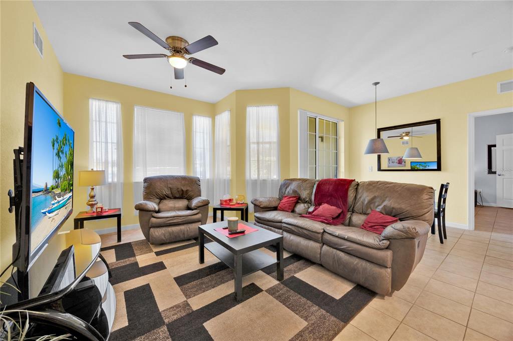 804 Terrace Ridge Circle, Unit 804 Davenport, FL 33896 - Photo 6 of 18 a living room with furniture a flat screen tv and a floor to ceiling window