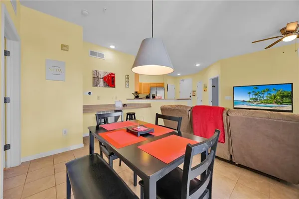 a room with stainless steel appliances kitchen island granite countertop a dining table chairs and a refrigerator