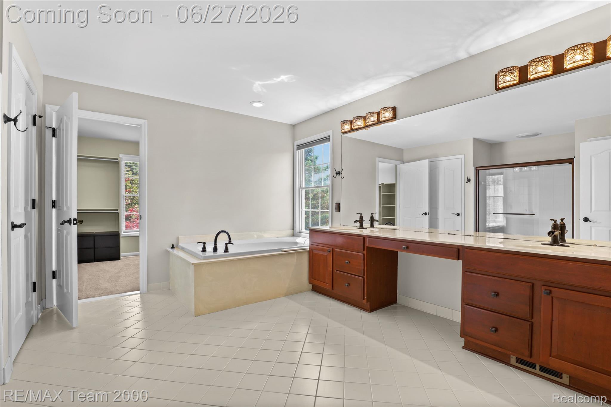 1248 Lasalle Road Canton, MI 48187 - Photo 56 of 67 Bathroom featuring dual wood-finish vanities with light countertops, a built-in garden tub, a large wall mirror, and white tile flooring