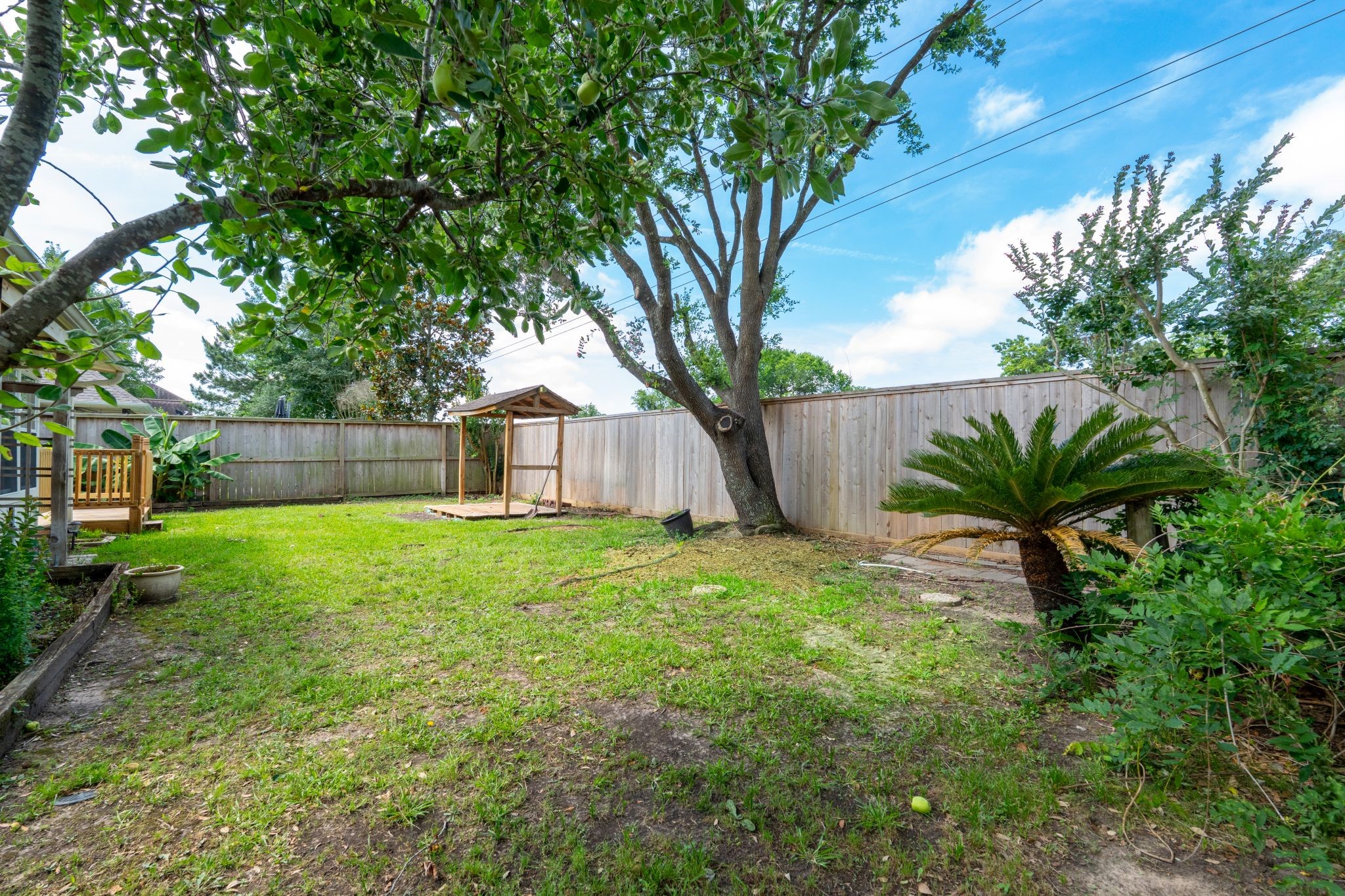 10619 Crownsedge Drive Spring, TX 77379 - Photo 34 of 38 This photo showcases a spacious backyard with a well-maintained lawn, a mature tree, and a wooden fence for privacy. There's a small wooden structure in the corner, ideal for storage or a play area. Lush greenery surrounds the space, creating a serene outdoor retreat.