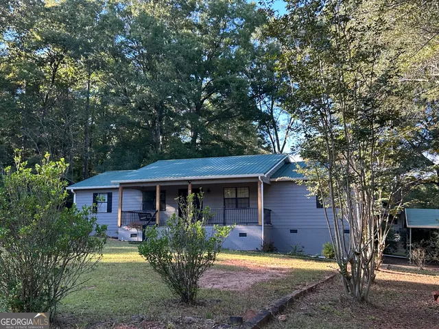 a view of a house with a yard tree and sitting area