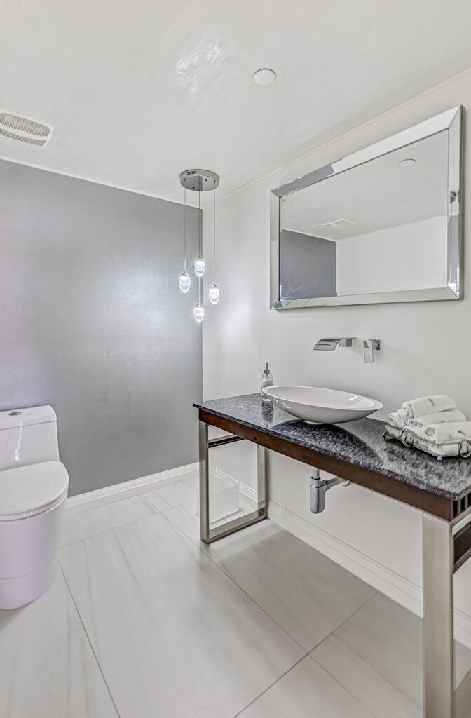 5280 North Ocean Drive, Unit 12F Singer Island, FL 33404 - Photo 56 of 66 a spacious bathroom with a granite countertop sink a toilet and mirror