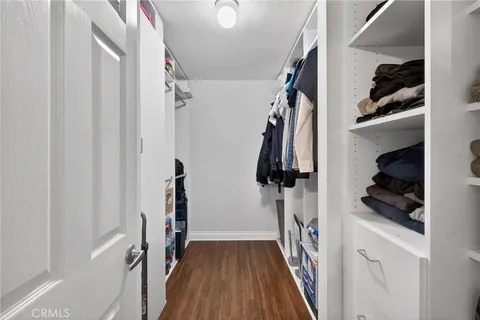 a walk in closet with wooden floor