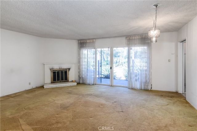a view of an empty room with a fireplace and a window
