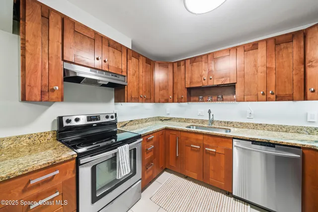 a kitchen with stainless steel appliances granite countertop a stove a sink dishwasher and cabinets with wooden floor