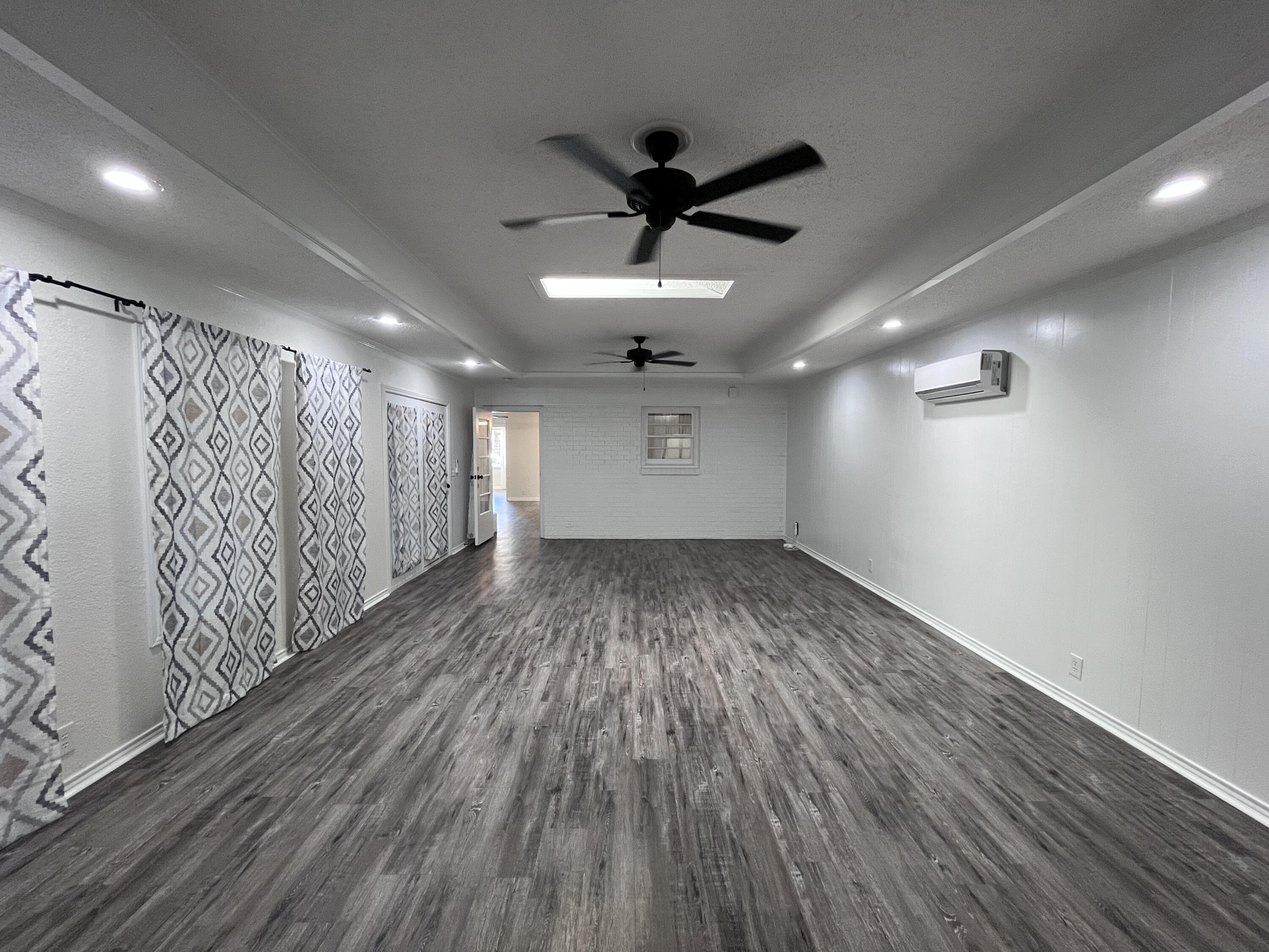 3612 55th Street Lubbock, TX 79413 - Photo 14 of 28 a view of a room with wooden floor a ceiling fan and windows
