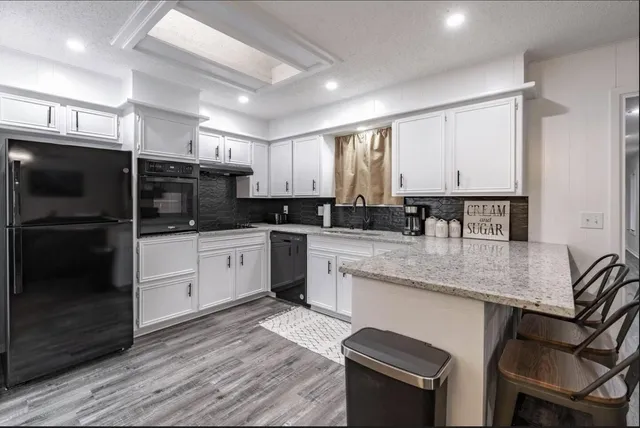 a kitchen with stainless steel appliances granite countertop a kitchen island hardwood floor sink and stove