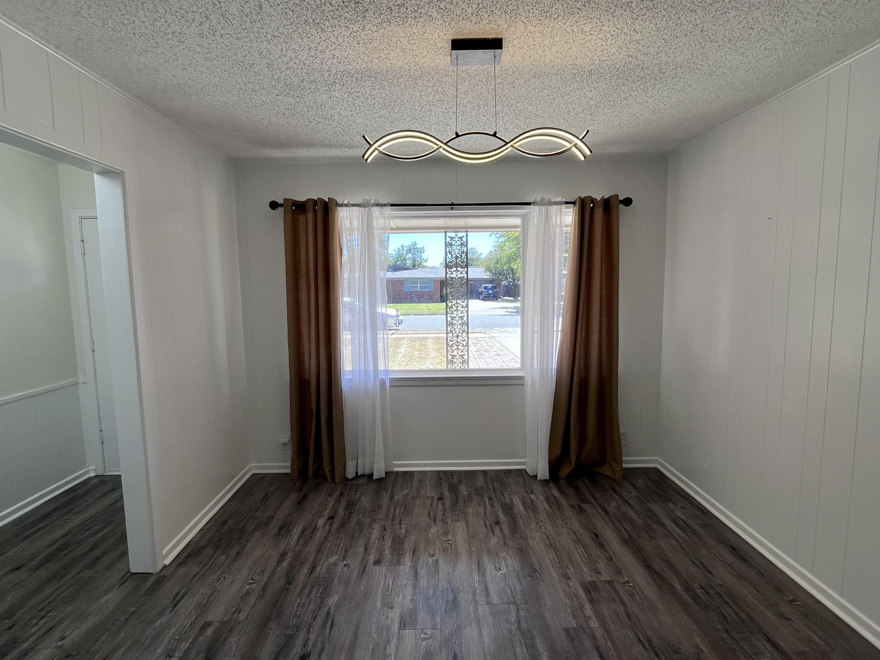 3612 55th Street Lubbock, TX 79413 - Photo 4 of 28 an empty room with wooden floor chandelier and windows